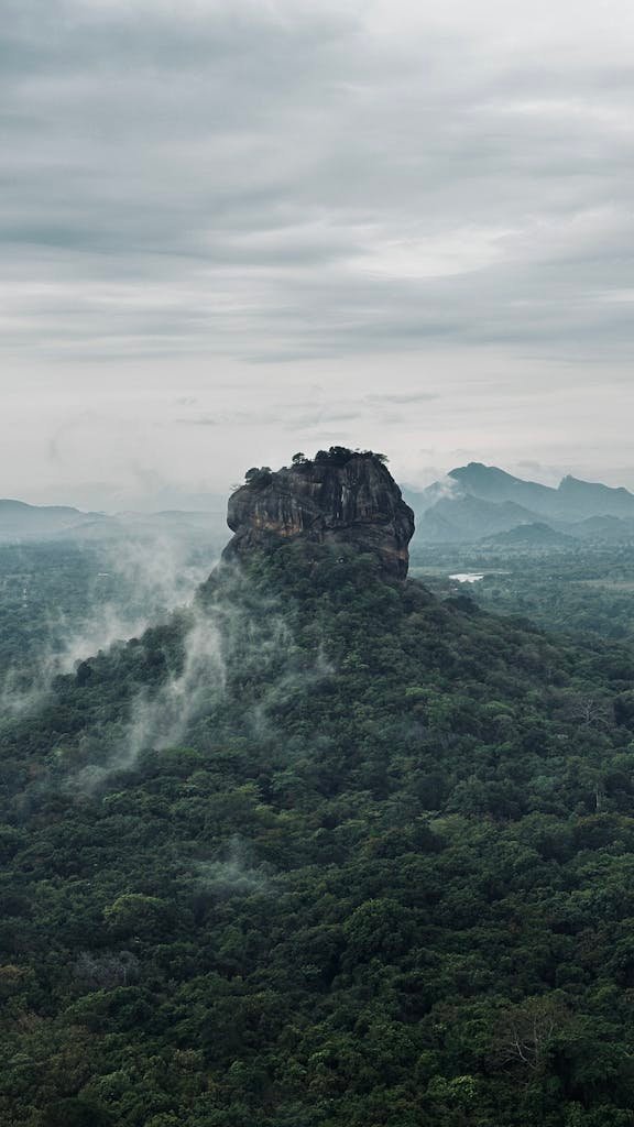 Dramatic aerial view of Sigiriya Rock, an iconic landmark in Sri Lanka surrounded by lush forest and mist during Sri Lanka itinerary in action