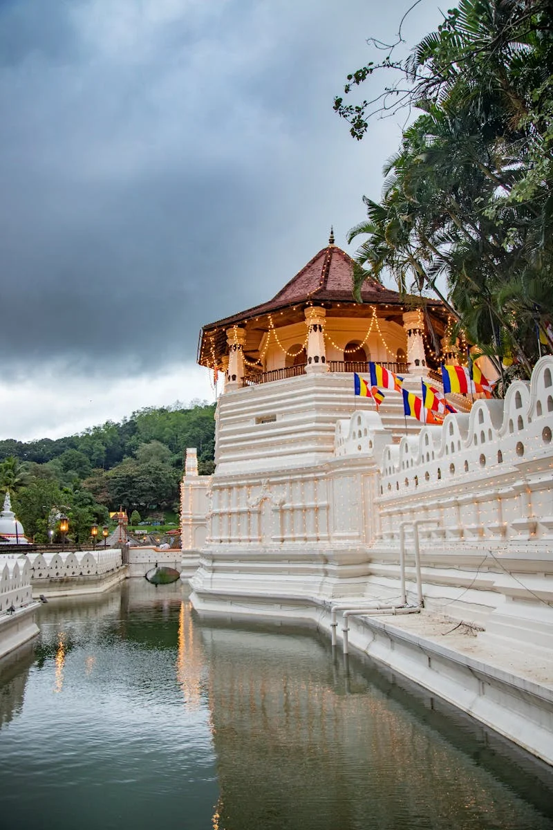 Beautiful view of a sacred temple reflecting in the river, surrounded by lush greenery, under a moody sky in Sri Lanka.