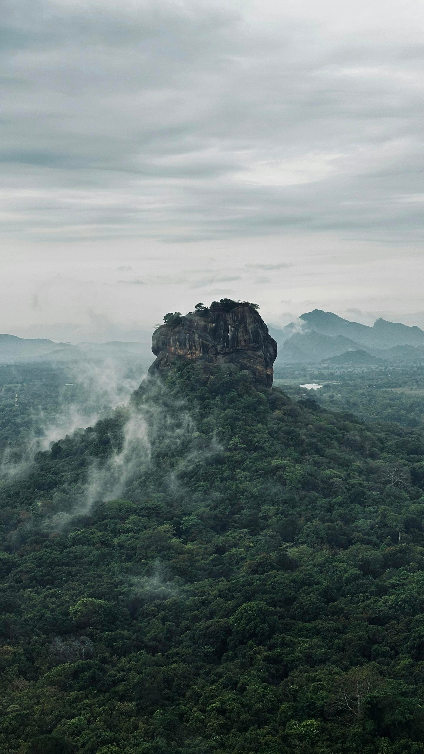 Dramatic aerial view of Sigiriya Rock, an iconic landmark in Sri Lanka surrounded by lush forest and mist during Sri Lanka itinerary in action